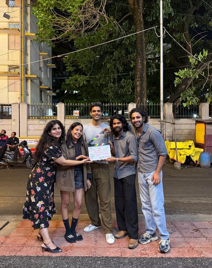 Group holding a film clapperboard on a street at night, wrapping a shoot